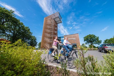 2 Radfahrer fahren vor der Globetrotter Lodge in den Hüttener Bergen